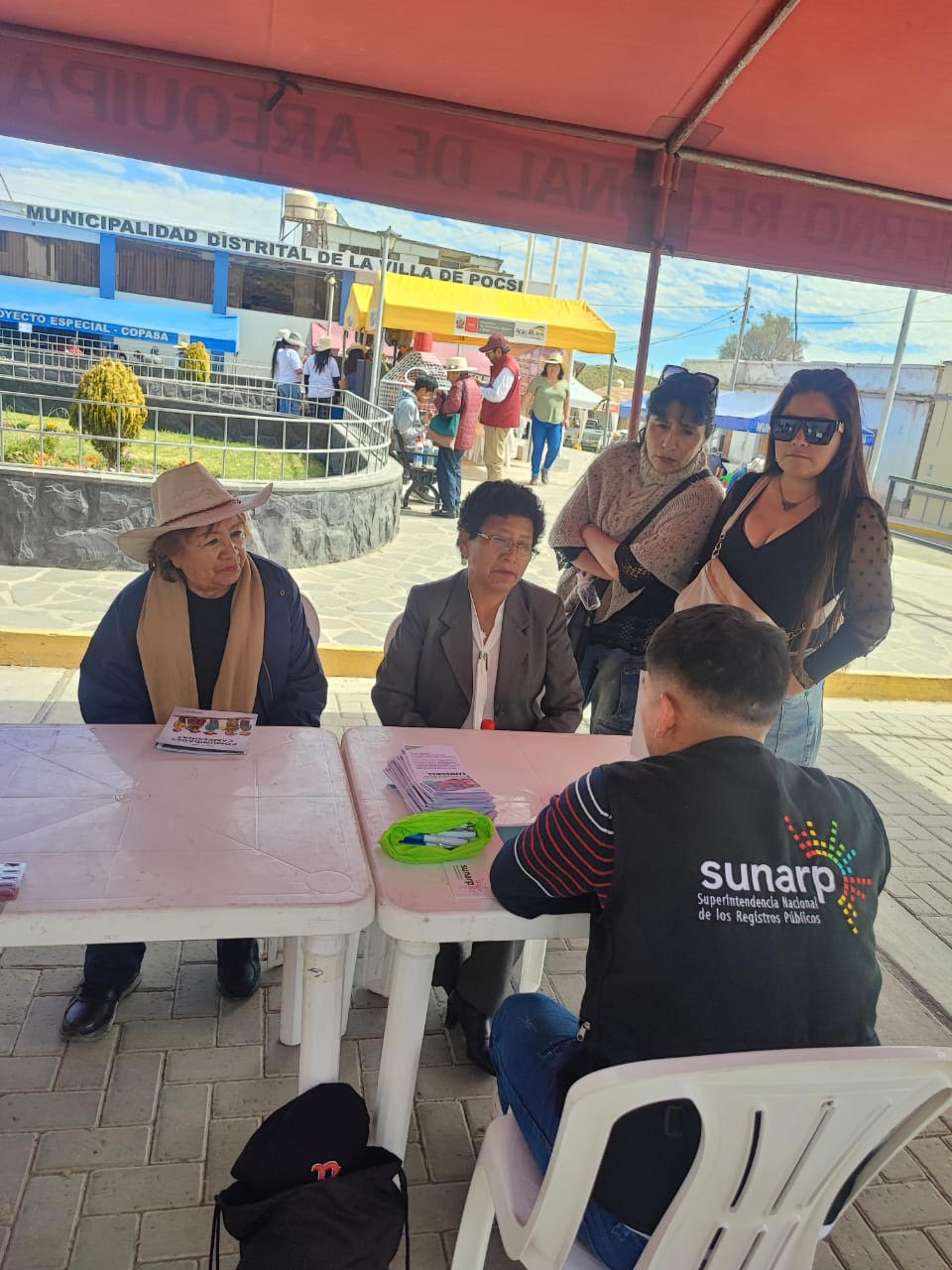 Foto de Un trabajador de Sunarp brinda información a cuatro mujeres en módulo de atención
