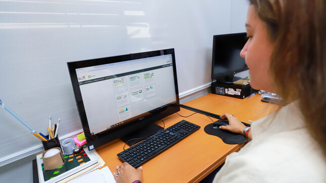 Foto de Trabajadora de Sunarp sentada frente a monitor de pantalla de una PC