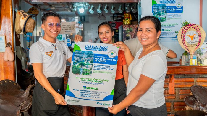 Personas de un local de servicios turísticos con afiche informativo