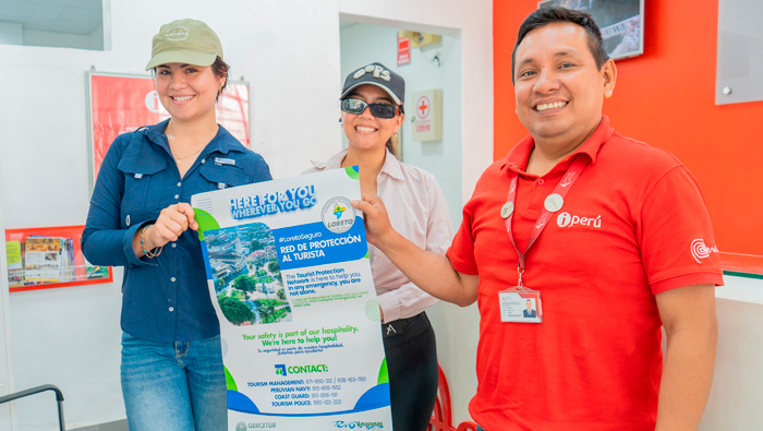 Personas de un local de servicios turísticos con afiche informativo