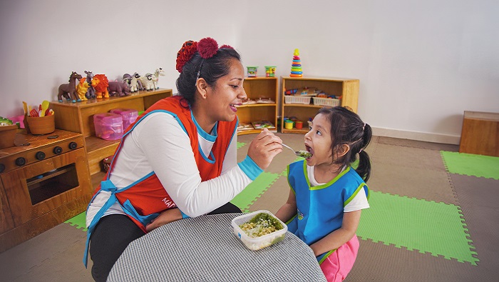 Madre cuidadora dándo de comer a niña
