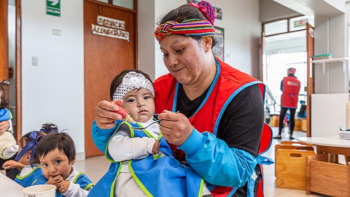 Madre cuidadora dándo de comer a niña