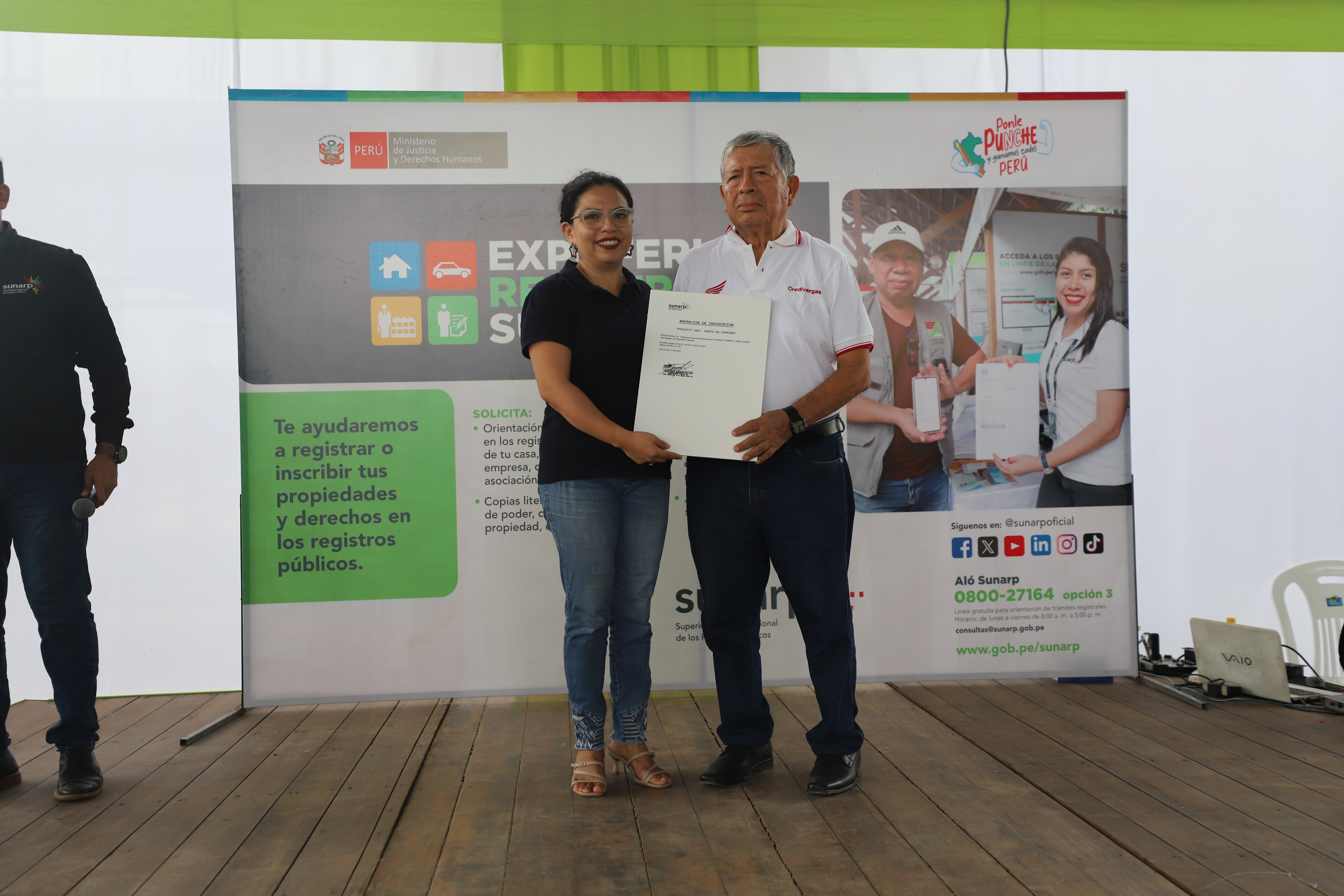 Foto de Dos personas muestran documento registral en Expoferia