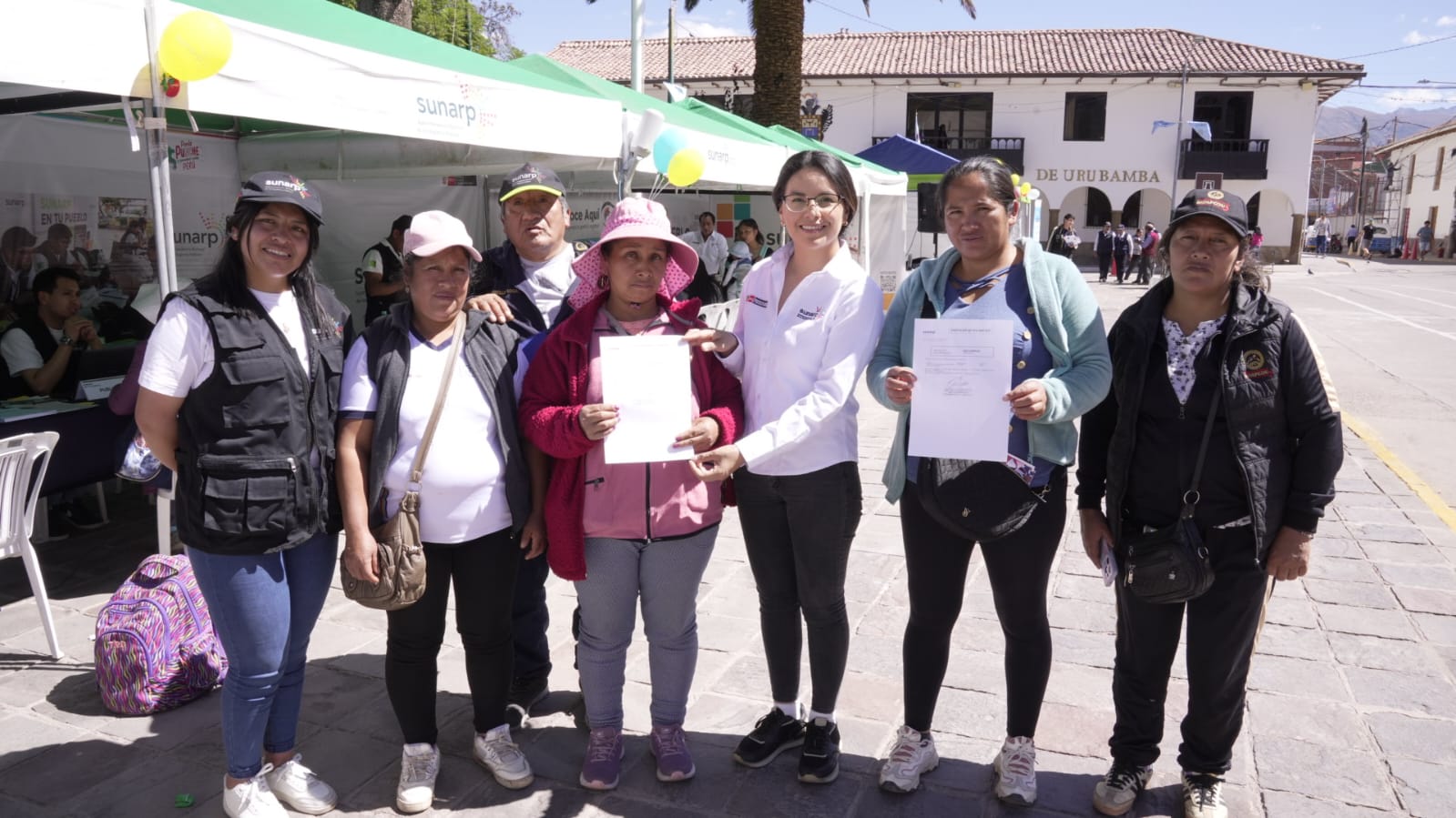 Foto de Trabajadores de Sunarp y pobladores de Cusco posan para la foto mostrando documentos registrales