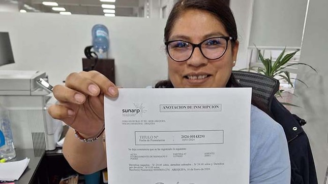 Foto de Servidora de Sunarp sostiene y muestra en sus manos documento registral