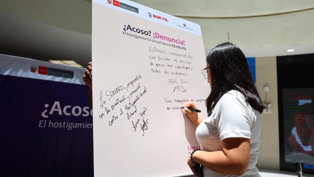 Foto de mujer firmando un pizarrón 